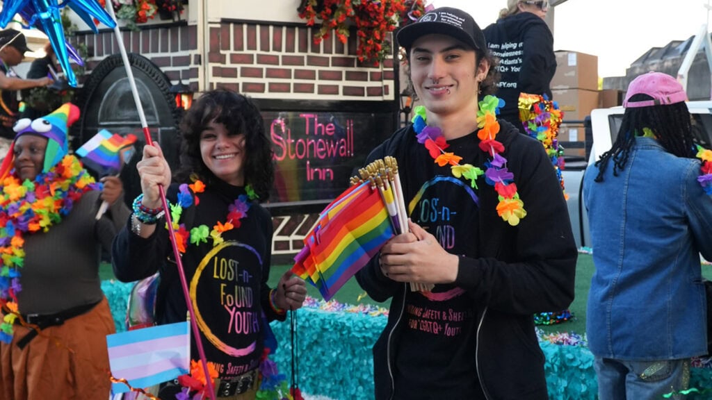 Two young adults pose with the Lost-N-Found Youth float in Atlanta’s Pride Parade, representing an organization that offers support for youth experiencing homelessness.